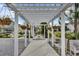 A charming pergola-covered walkway with hanging plants and seating, inviting relaxation at 312 Greenhouse, Summerville, SC 29485