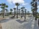 Outdoor common area featuring picnic tables, a fire pit, palm trees, and gravel surfaces, creating inviting community spaces at 351 Gnarly Oak Ln, Summerville, SC 29485