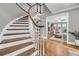 Elegant curved staircase featuring hardwood treads, white risers, and a decorative railing, leading to an open-concept living area at 3555 Colonel Vanderhorst Cir, Mount Pleasant, SC 29466