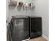 Laundry room featuring a modern, dark washer and dryer, and white wire shelving for storage at 470 Sanctuary Park Dr, Summerville, SC 29486