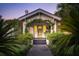 Inviting home exterior at dusk, showcasing a charming entryway with climbing plants and a well-lit porch at 66 Darlington Ave, Charleston, SC 29403