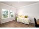 Sunlit bedroom with hardwood floors, a cheerful quilt, and views of the neighborhood at 6972 Pumpkinseed Dr, Johns Island, SC 29455