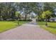 Long brick driveway leading to a beautiful home surrounded by mature trees and a well-manicured lawn at 7879 Gull Bay Dr, Awendaw, SC 29429