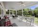 Inviting screened porch with rocking chairs, ceiling fans, and outdoor dining area overlooking the lush yard at 7879 Gull Bay Dr, Awendaw, SC 29429