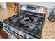 Close-up of a stainless steel gas stove top with four burners and granite countertop at 106 Sago Ct, Summerville, SC 29486