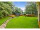 Lush backyard with large grassy area, a trampoline, a fire pit, and a path at 112 Fox Chase Dr, Goose Creek, SC 29445