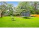 A large grassy backyard with a trampoline and boat trailer sitting behind a wooden fence at 112 Fox Chase Dr, Goose Creek, SC 29445