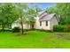View of the home's exterior featuring green grass, mature trees and a two-car garage at 112 Fox Chase Dr, Goose Creek, SC 29445