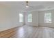Bright main bedroom featuring wood-look floors, a ceiling fan, and three large windows with wooded views at 1552 Harborsun Dr, Charleston, SC 29412