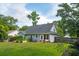 Back exterior view with a patio seating area and a well-maintained lawn surrounded by lush trees at 1928 Gasque St, Johns Island, SC 29455