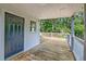 Cozy covered porch with wooden decking and classic white railing, door to interior at 208 State St, Walterboro, SC 29488