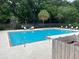 Community swimming pool surrounded by trees, lounge chairs, and a privacy fence at 2494 Etiwan Ave # 9-D, Charleston, SC 29414