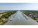 Aerial view of riverfront homes featuring private docks and scenic waterway with boat under clear, blue skies at 2619 Buccaneer Rd, Isle of Palms, SC 29451