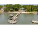 Waterfront home featuring a private dock extending to sandy beach, complemented by lush green vegetation and blue skies at 2619 Buccaneer Rd, Isle of Palms, SC 29451