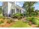 The backyard shows lush landscaping, a brick patio, and a screened porch at 27 Watroo Pt, Daniel Island, SC 29492