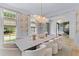 Light filled dining room with marble table, bubble chandelier, and view into the living room at 27 Watroo Pt, Daniel Island, SC 29492