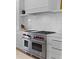 Gourmet kitchen features a Wolf range, custom backsplash, and white cabinetry at 27 Watroo Pt, Daniel Island, SC 29492