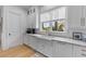 Farmhouse sink with white cabinetry, marble countertops, and stainless steel faucet under window at 27 Watroo Pt, Daniel Island, SC 29492