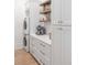 Laundry room features white cabinetry, floating shelves, and stacked washer and dryer at 27 Watroo Pt, Daniel Island, SC 29492