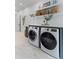 Laundry room with white, front load washer and dryer units, white brick flooring and shelves at 27 Watroo Pt, Daniel Island, SC 29492