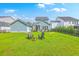 Spacious backyard with lush green grass, fire pit, Adirondack chairs, and manicured landscaping at 2710 Mcfadden Way, Johns Island, SC 29455