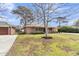 Beautiful brick home with a lush green lawn, mature trees, and charming front porch with classic rocking chairs at 303 Gippy Dr, Summerville, SC 29486