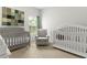 Bright Bedroom featuring two white cribs and a comfortable gray rocking chair at 3431 Great Egret Dr, Johns Island, SC 29455