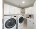 Functional laundry room equipped with modern washer and dryer, complemented by ample cabinet space at 4007 Oxeye, Johns Island, SC 29455