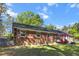 Backyard view of a charming brick home with a patio, grill, and lush green lawn; ideal for entertaining at 411 Dogwood Circle, Summerville, SC 29485