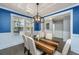 Stylish dining room featuring an elegant light fixture, wood table, wainscoting and blue accent wall at 414 Hamlet Cir, Goose Creek, SC 29445