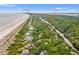 Sweeping aerial view of coastal home nestled amongst lush trees near beach and adjacent to a tranquil river at 43 Surfsong Rd, Kiawah Island, SC 29455