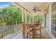 Covered back porch with dining table, ceiling fan, and serene view of the surrounding trees at 43 Surfsong Rd, Kiawah Island, SC 29455