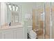Well-lit bathroom featuring a vanity, stone countertop, glass shower, and white tiling at 43 Surfsong Rd, Kiawah Island, SC 29455