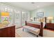 Sun-filled bedroom with large windows, wood floors, ceiling fan and seating bench at 43 Surfsong Rd, Kiawah Island, SC 29455