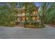 Elegant three-story home with a brick staircase leading to a welcoming front porch surrounded by lush greenery at 43 Surfsong Rd, Kiawah Island, SC 29455