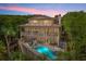 Elegant three-story home with a private pool and deck, illuminated at dusk, showcasing outdoor living spaces at 43 Surfsong Rd, Kiawah Island, SC 29455