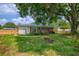Backyard view of brick home with small deck, fire pit, and large shade tree offering a peaceful retreat at 444 Clarine Dr, Goose Creek, SC 29445