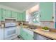 Charming kitchen offers green cabinets, stainless steel sink, and a window, blending vintage charm with modern convenience at 444 Clarine Dr, Goose Creek, SC 29445