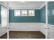 Home office featuring wood floors, white wainscoting, teal walls, and three bright windows at 661 Black Pine Rd, Moncks Corner, SC 29461