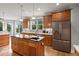 Well-lit kitchen featuring wood cabinets, stainless steel appliances, and a kitchen island with a black countertop at 8605 Refuge Point Cir, North Charleston, SC 29420