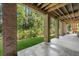 Covered patio with brick supports offering a serene outdoor view of the lush, green landscape and wooded areas at 8605 Refuge Point Cir, North Charleston, SC 29420