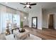 Bright living room featuring wood floors, a ceiling fan, and a large window with white curtains at St, Saint George, SC 29477