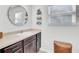 Well lit bathroom featuring dark wood cabinets, round mirror, and woven storage basket at 100 Runnels Cv, Summerville, SC 29485