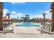 Expansive community pool and splash pad with palm trees, lounge chairs, and umbrellas on a sunny day at 111 Medford St, Summerville, SC 29486