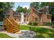 Backyard with a wooden deck, stone patio, and brick exterior. The house has two chimneys at 125 Drayton Dr, Summerville, SC 29483