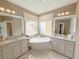 Bright bathroom features a soaking tub between two vanities, neutral walls, and bright lighting at 157 Village Ponds Dr, Summerville, SC 29483