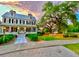 Grand two-story home with a charming front porch and lush landscaping at sunset at 157 Village Ponds Dr, Summerville, SC 29483