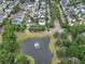 A high-angle view of a community featuring tree-lined streets and a tranquil pond with a fountain at 205 White Gables Dr, Summerville, SC 29483