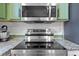 A close-up of a stainless steel stovetop and microwave with green cabinets in the background at 205 White Gables Dr, Summerville, SC 29483