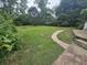 Lush backyard featuring a concrete walking path, foliage, and mature trees at 207 Cedar St, Saint George, SC 29477